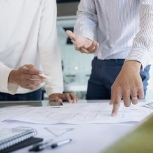 Image of engineer meeting for architectural project working with partner and engineering tools on workplace.